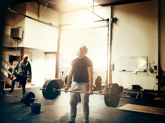 Fit mature man straining to lift weights at the gym
