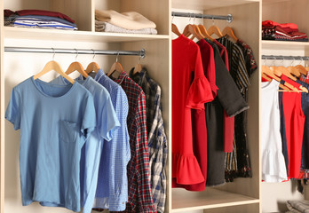 Obraz premium Hangers with different clothes in wardrobe closet