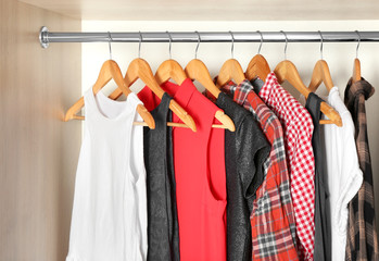 Hangers with different clothes in wardrobe closet