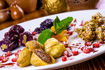Dried fruits, sunflower seed brittle, walnut Georgian churchkhela on white plate