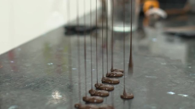 Jets of chocolate mass are falling on the table. A waterfall drops out of the container from a mixture of cocoa, butter and sugar. slow motion slowmotion