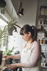 Smiling female florist arranging flowers in her shop window