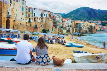 Selbstklebende Fototapeten Palermo Young couple sitting at beach in Cefalu Sicily  © Roman Babakin