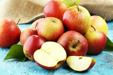 Ripe red apples with leaves on blue background.