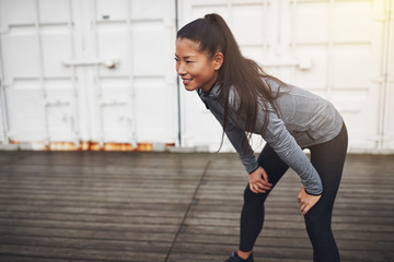 Smiling Asian woman in sportswear taking a break from running