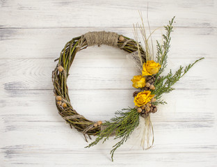 Wreath from a vine with roses. Handmade deco. Wreath of real twigs on a wooden background