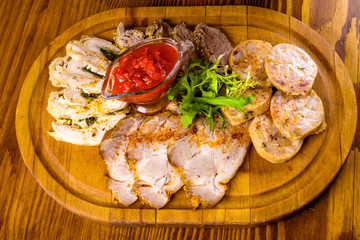 Meat platter with tomato sauce on wooden cutting board. Top view
