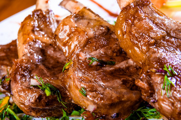 Rack of lamb with vegetables and herbs on white plate