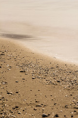 Golden sand meeting calm sea shining in sunrise light