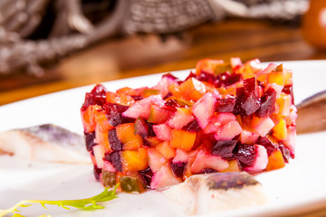 Russian beetroot salad with herring on white plate
