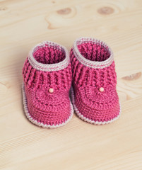 Cute Crochet baby booties  on wooden background
