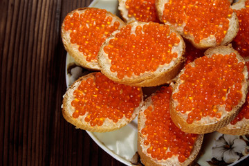 Sandwiches with butter and red caviar on wooden table