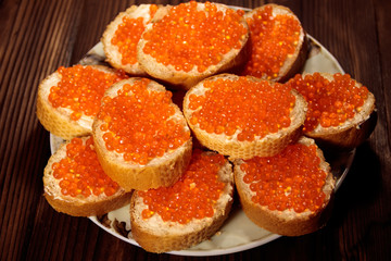 Sandwiches with butter and red caviar on wooden table