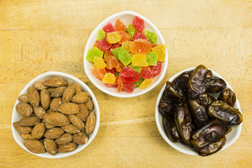 Bowls with additions to cakes and desserts: dried dates, candied pineapple and shelled almonds. View from above.