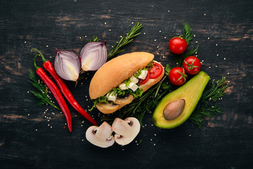 Burger, sandwich with feta cheese, mushrooms and lettuce leaves. On a wooden background. Top view....
