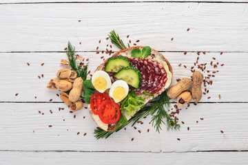 Burger, sandwich with salami, quail eggs and cherry tomatoes. On a wooden background. Top view. Copy space.