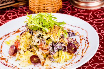 Salad with chicken, vegetables and walnut sauce on white plate