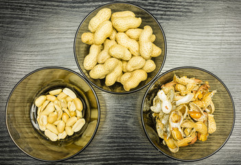 Peeling peanuts. A bowl of peels and clean peanuts on the plate. View from above.