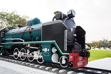 An old steam locomotive in black and green color is shown in the park for people to take a look. 