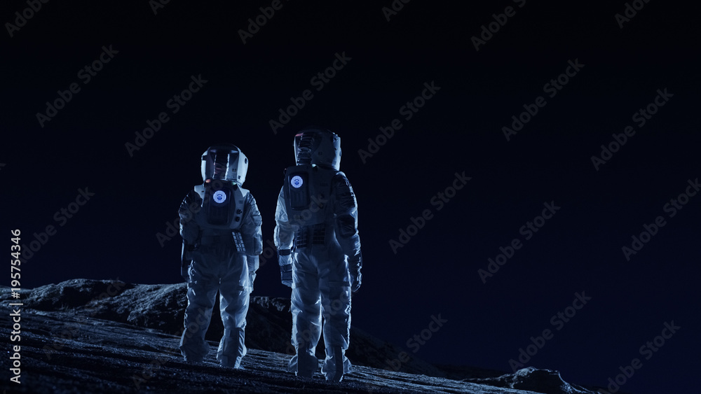 Wall mural two astronauts in space suits stand on the alien planets observing extraterrestrial terrain. space t