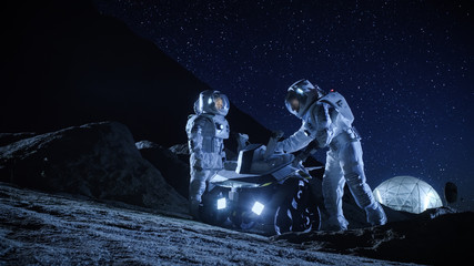 Two Astronauts in Space Suits on an Alien Planet Prepare Space Rover for Surface Exploration Mission. Futuristic Concept about Space Colonization.