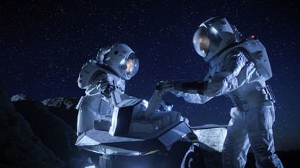 Two Astronauts in Space Suits on an Alien Planet Prepare Space Rover for Surface Exploration Mission. Futuristic Concept about Space Colonization.