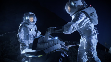 Two Astronauts in Space Suits on an Alien Planet Prepare Space Rover for Surface Exploration Mission. Futuristic Concept about Space Colonization.