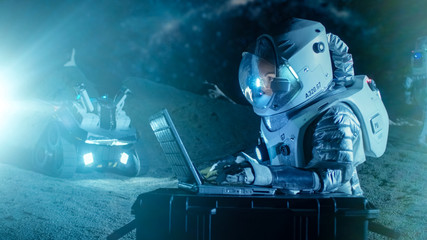 Female Astronaut Wearing Space Suit Works on a Laptop, Exploring Newly Discovered Planet,...