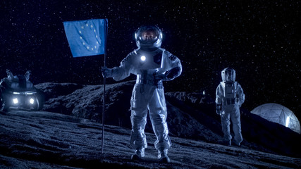 Female Astronaut Planting Flag of Europe Union on the Alien Planet. In the Background Her Crew Member, Living Station and Exploration Rover. Space Travel and Solar System Colonization Concept.