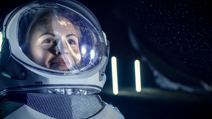 Portrait of the Beautiful Female Astronaut on the Alien Planet. Earth Reflection on her Helmet. In the Background Living Habitat. Space Travel, Extraterrestrial and Solar System Colonization Concept.