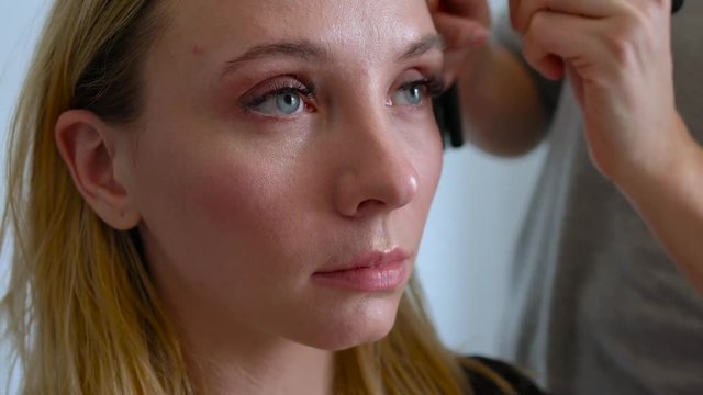 make-up artist applies powder and makes the correction of the face shape to the girl