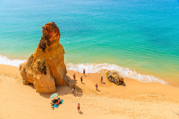 ALGARVE COAST, PORTUGAL - MAY 14, 2015: Tourists fishing on Praia da Rocha beach with golden color rocks in Portimao town, Portugal.