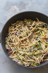 Trofie pasta with muschrooms leek and creme fraiche. Pan on blue and gray background. 