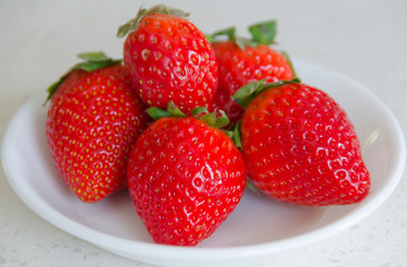 A small white bowl filled with fresh whole strawberries