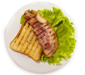 grilled bacon with toast on lettuce leaves. White isolated background.