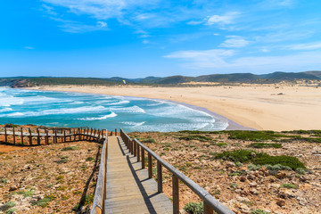 Fototapeta na wymiar Wooden walkway to beautiful Praia da Bordeira beach, popular place to do kite surfing, Algarve, Portugal