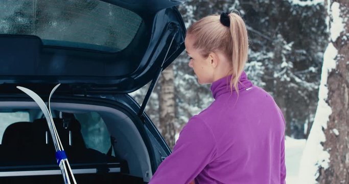 Caucasian female athlete walking towards her SUV after cross-country ski training. 4K UHD 60 FPS SLO MO