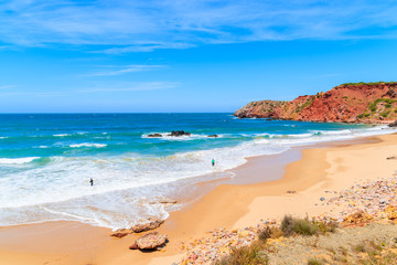 Fototapeta na wymiar Surfers on Amado beach with big sea waves, Algarve, Portugal