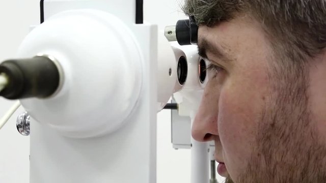 Patient in ophthalmology clinic. Man looks in synoptophore - ophthalmic instrument, used for diagnosing imbalance of eye muscles and treating them by orthoptic methods, for treatment of strabismus