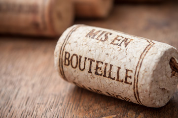 closeup of cork wine stopper with text - bottled on wooden table background  (traduction text in french - mis en bouteille) © pixarno