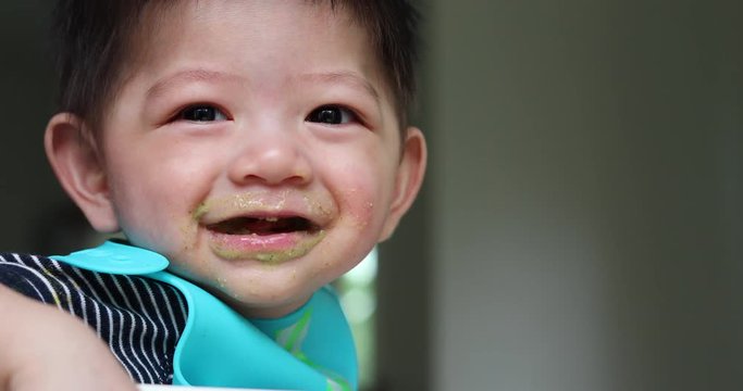cute baby happy eating meal puree with mother, close-up smile face