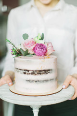 Wedding cake decorated with flowers in the hands of a pastry chef