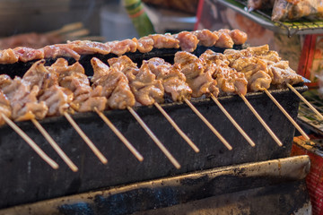 Roasted Pork or barbecue pork Toast grill on roaster at street market, street food. Roasted Pork with wood stalk is yummy and only in Thailand	