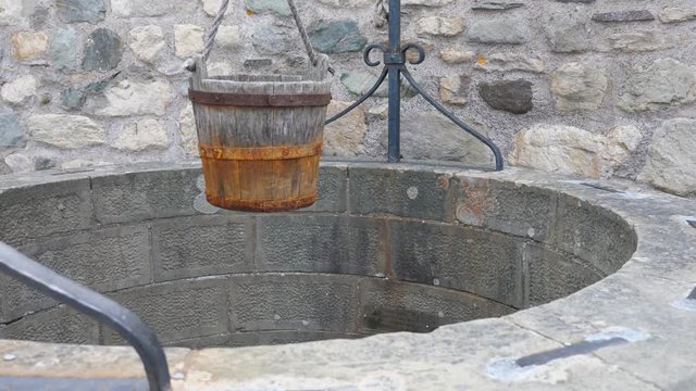 Old stone water well with a wood bucket