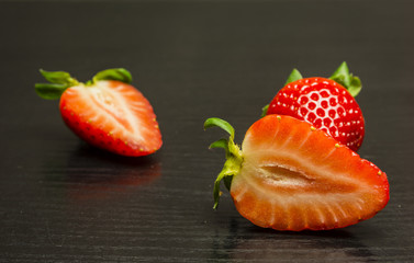 Cut ripe red strawberry on a wooden background.