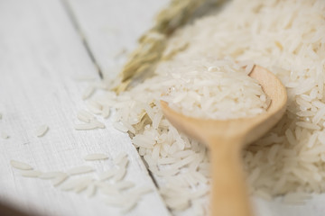 Soft focused of wooden spoon filled with rice placed on wooden background.