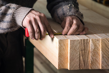 hand of a carpenter taking measurement of a wooden
