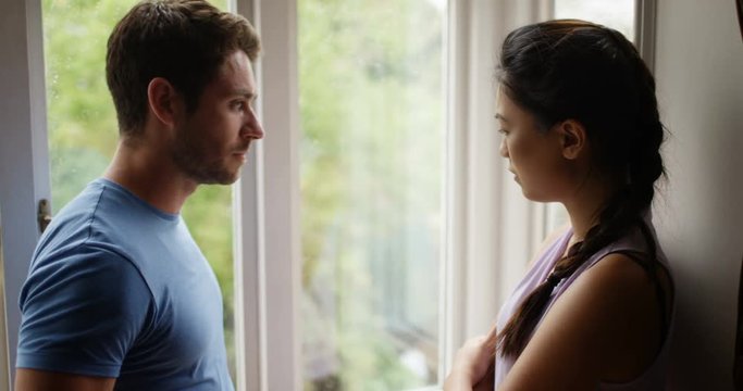 4K Sad couple standing next to window on a rainy day making up after relationship problems. Slow motion.