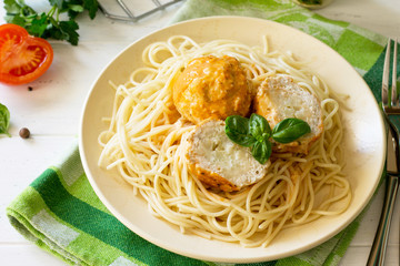 Meat balls turkey with cauliflower in tomato sauce and spaghetti on a wooden table.