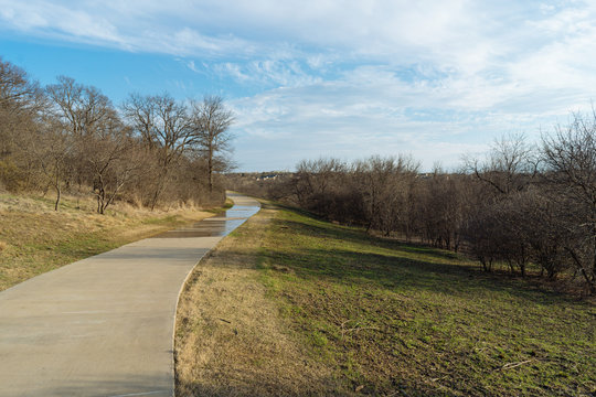 Concrete path and trees in the spring evening in the city park in Texas